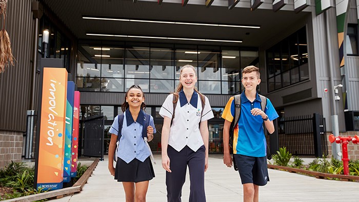 Three students in front of a school building.